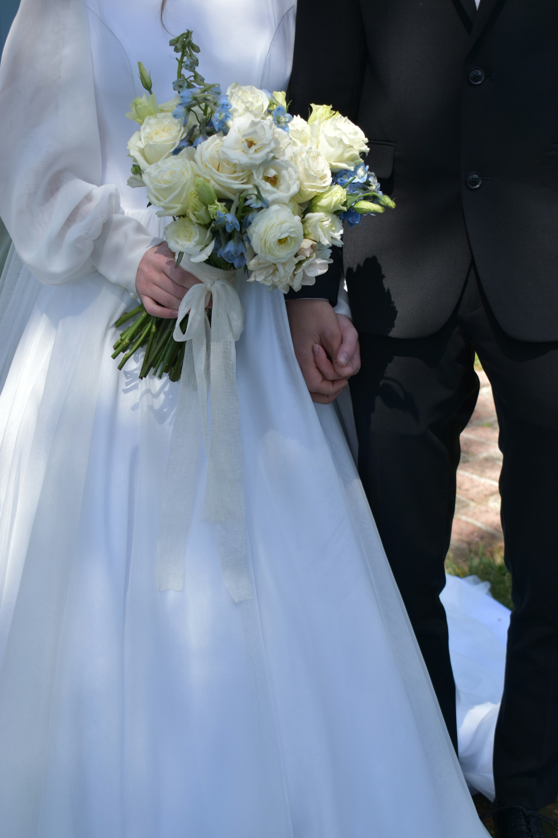 Newlyweds holding a white and blue bouquet